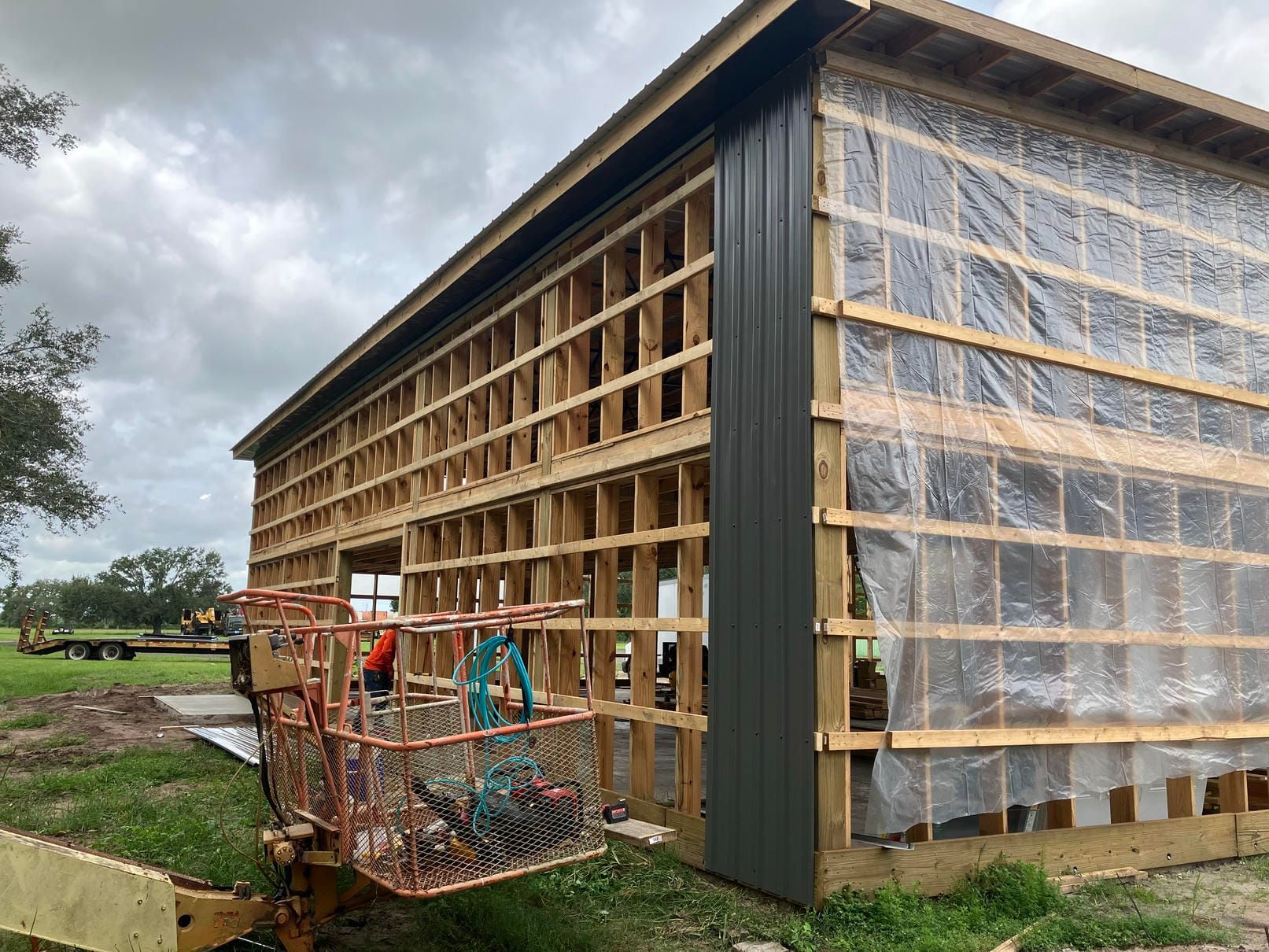 Partly built wooden shed with transparent tarp walls and a grassy yard under cloudy skies