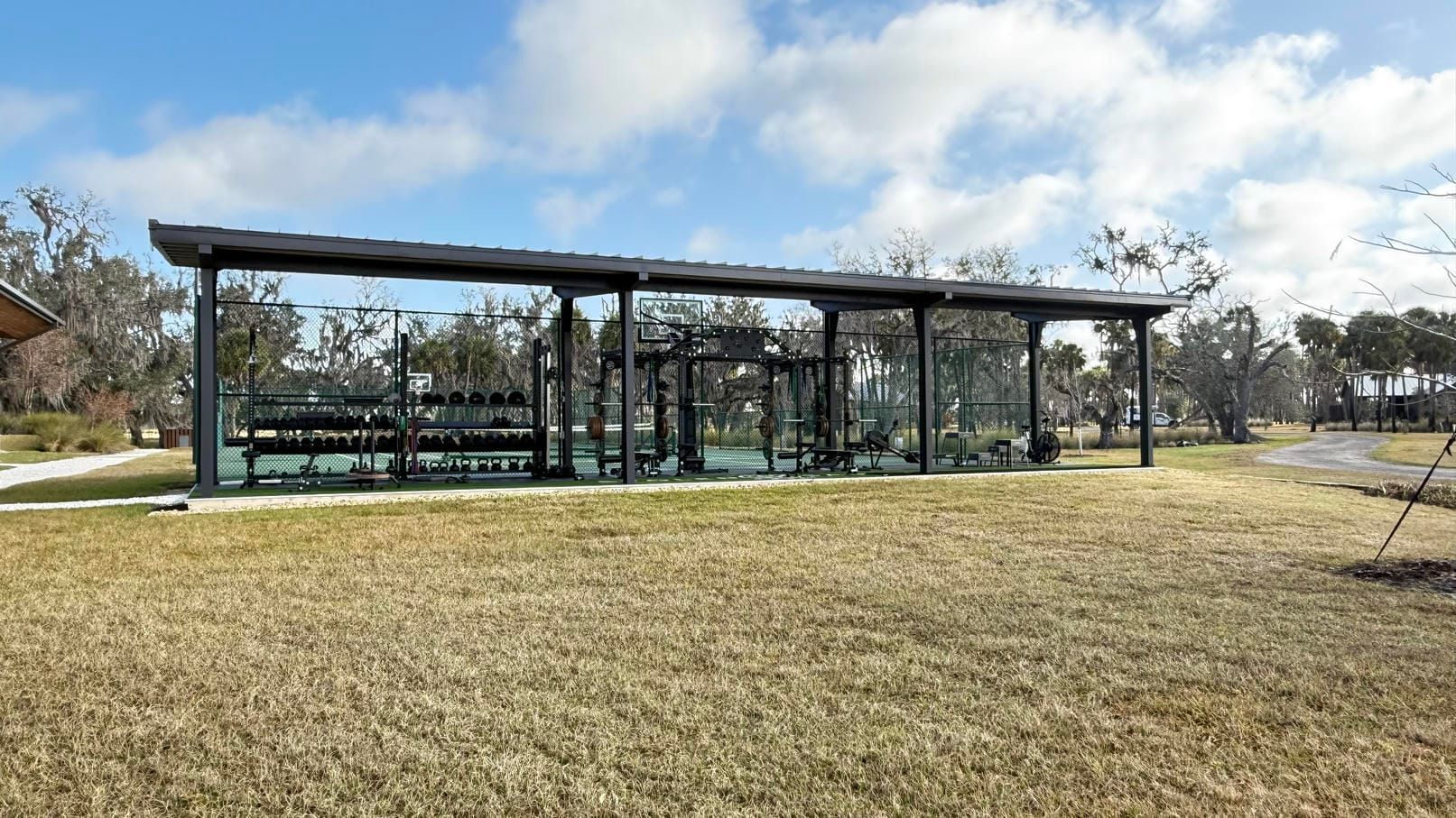 Open-air pavilion with picnic tables in a grassy park under a partly cloudy sky