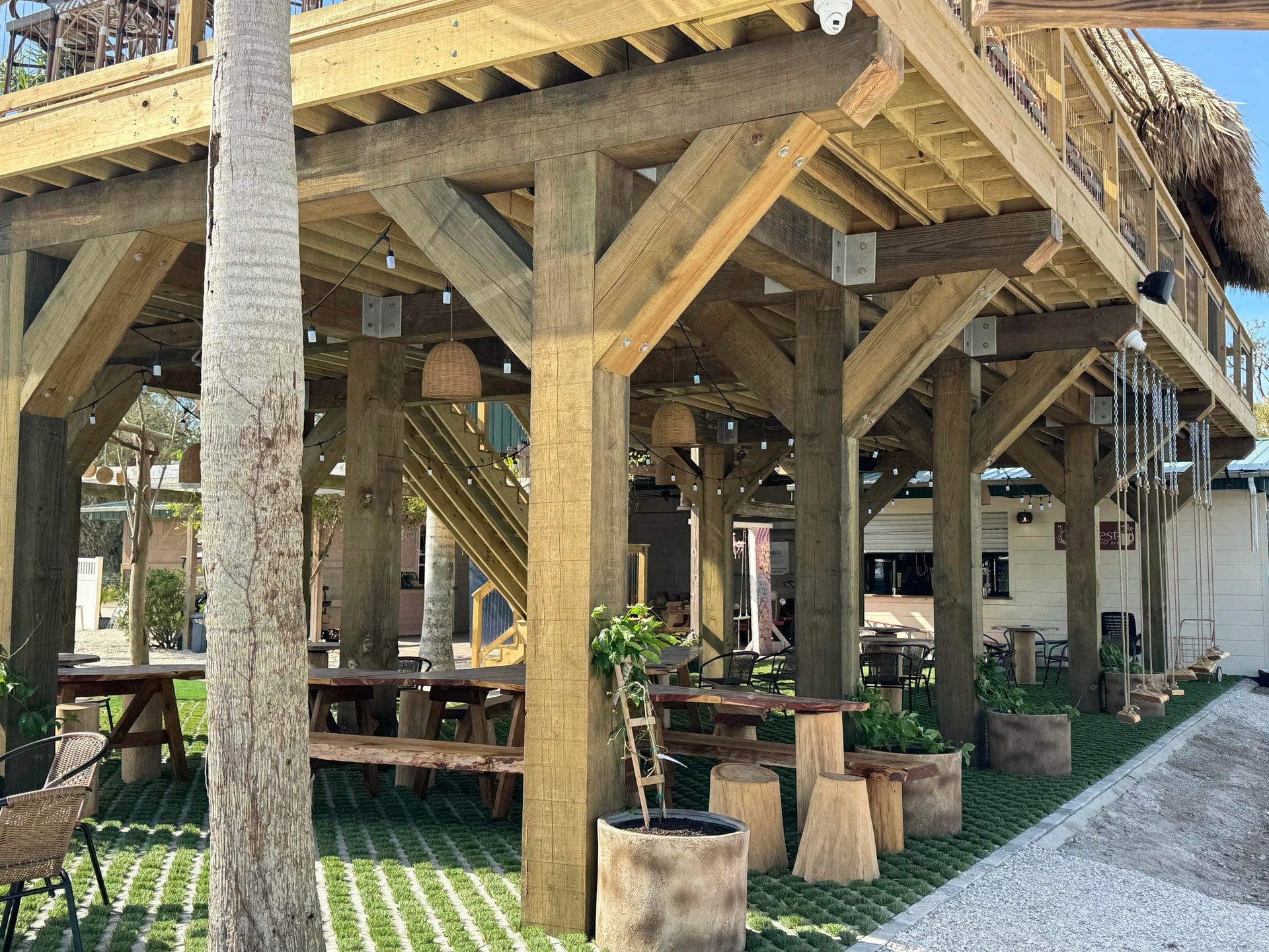 Rustic wooden pavilion with benches and posts beside a gravel path under trees