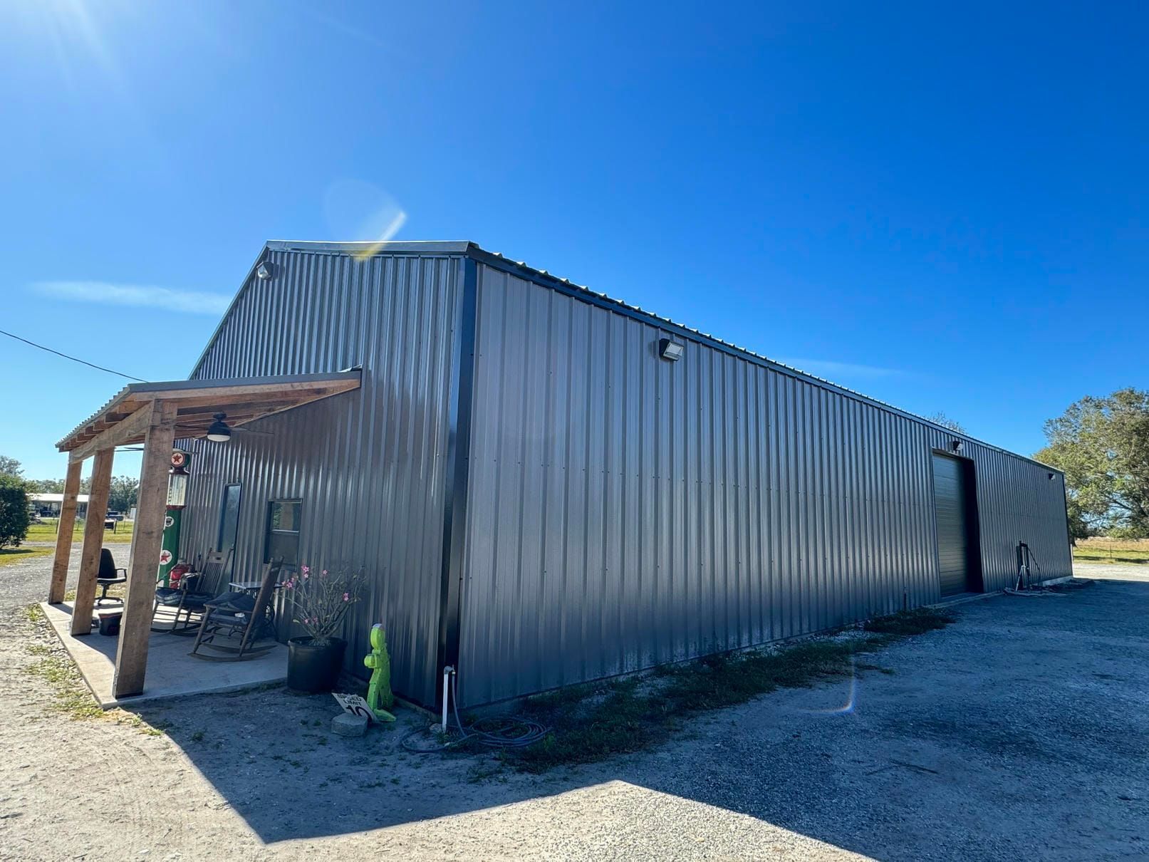Corrugated metal shed in a sunny gravel lot under a clear blue sky