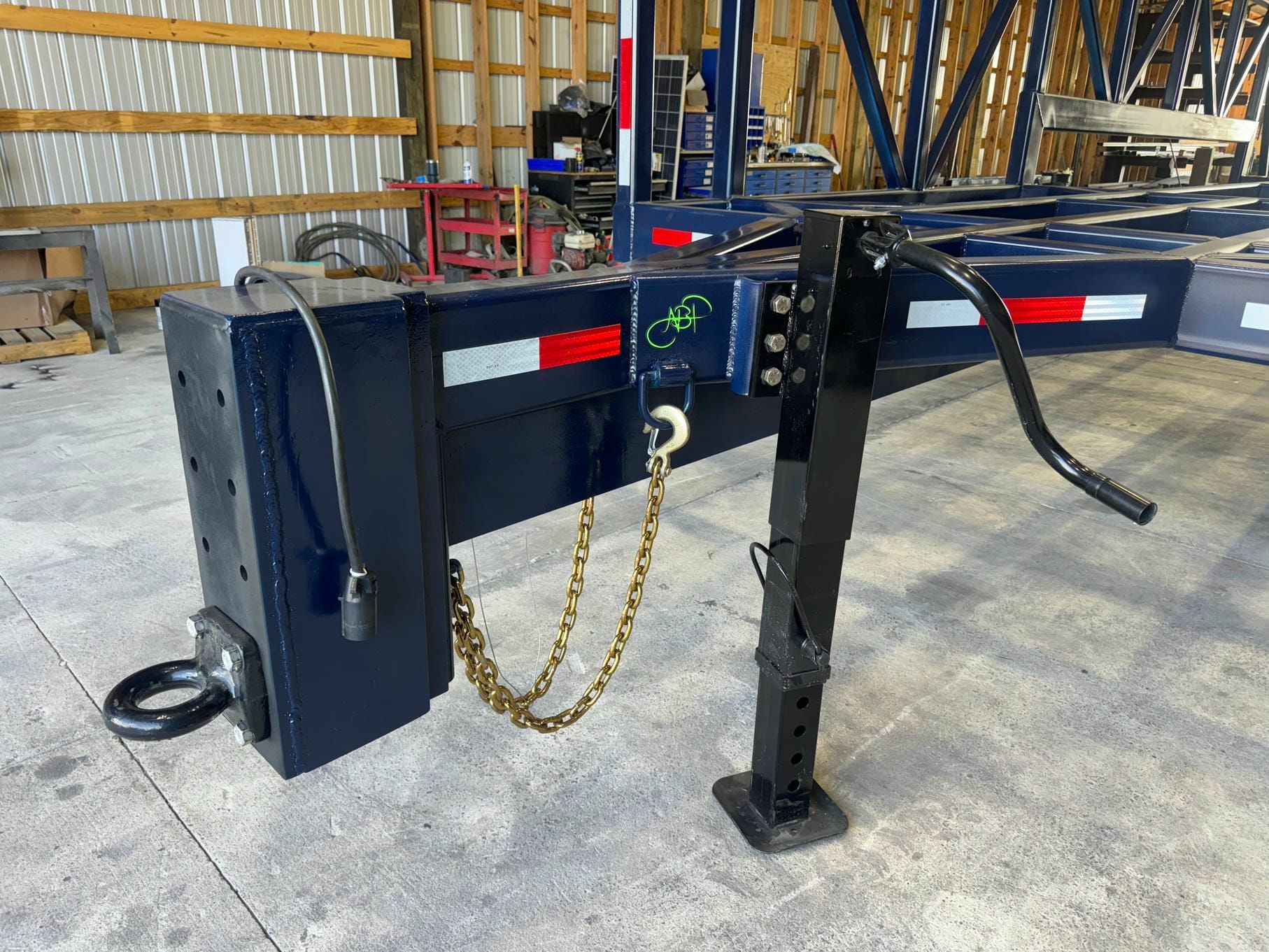 Industrial trailer hitch in a warehouse, with chains, wiring, and a black support leg.