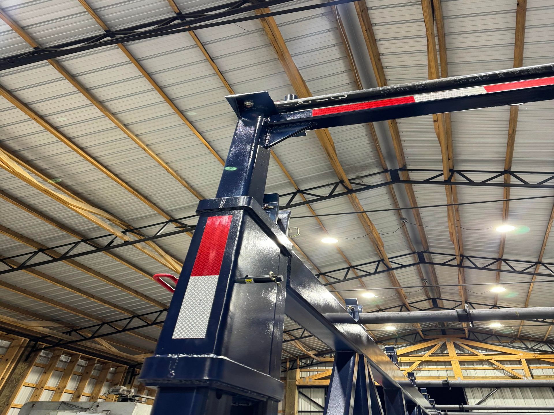 Industrial warehouse ceiling with a large blue overhead gantry crane under metal roof trusses