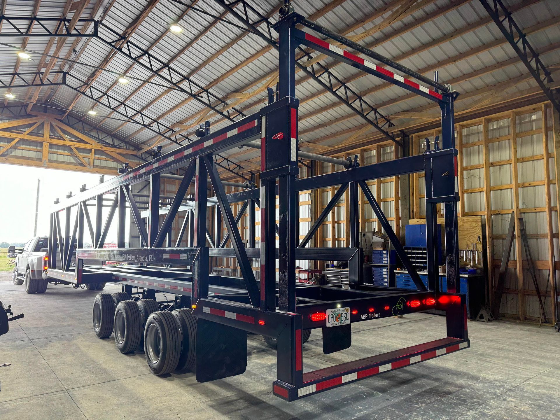Black flatbed trailer with steel frame inside a warehouse