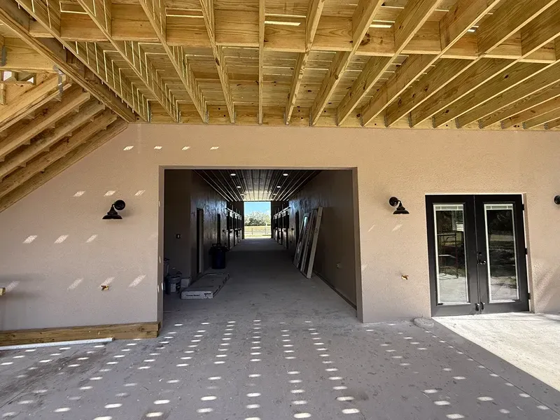 Covered patio with exposed wood beams, central hallway, and glass doors on the right.