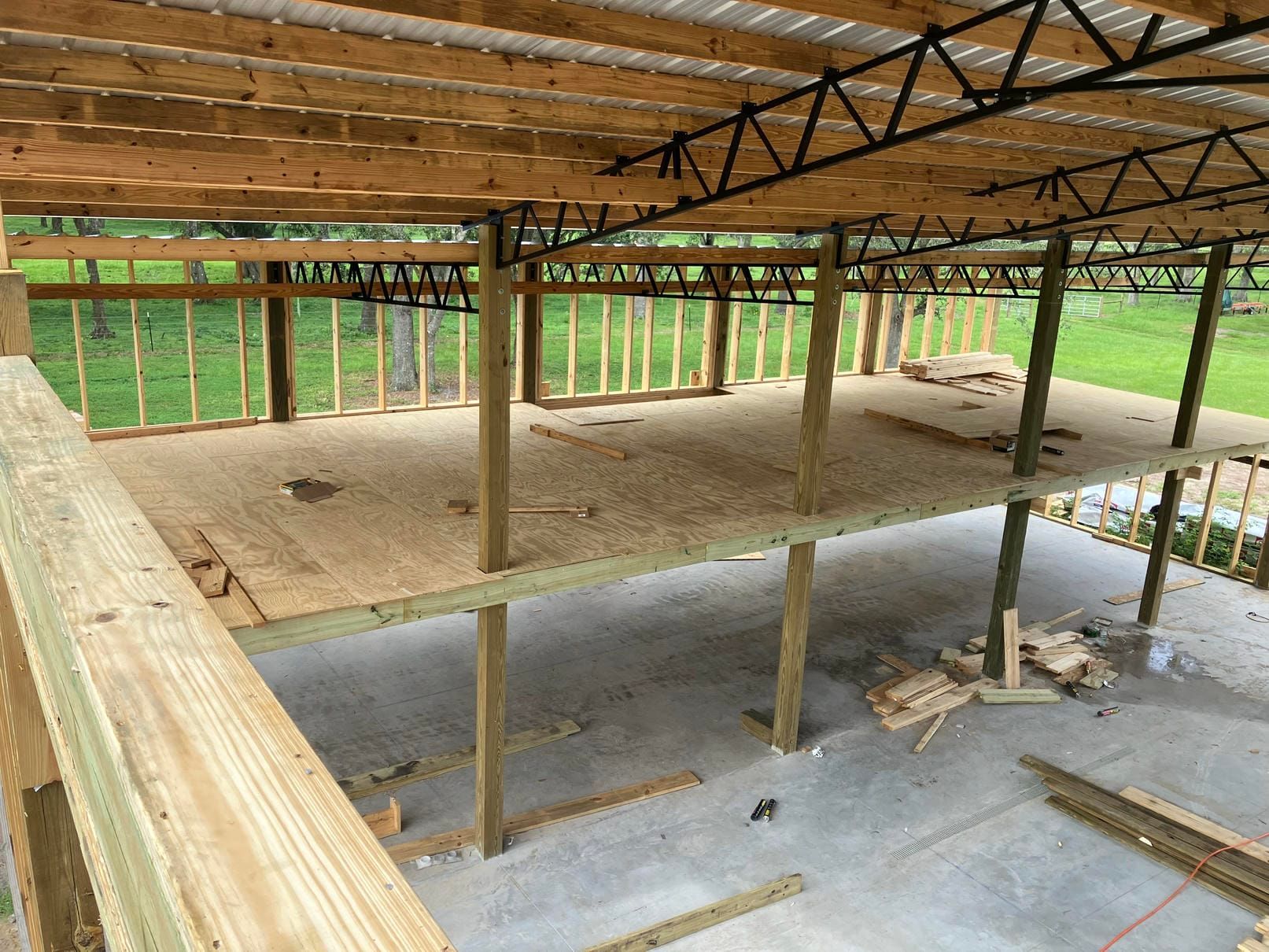Partially built wooden house with exposed framing and unfinished concrete floor outdoors