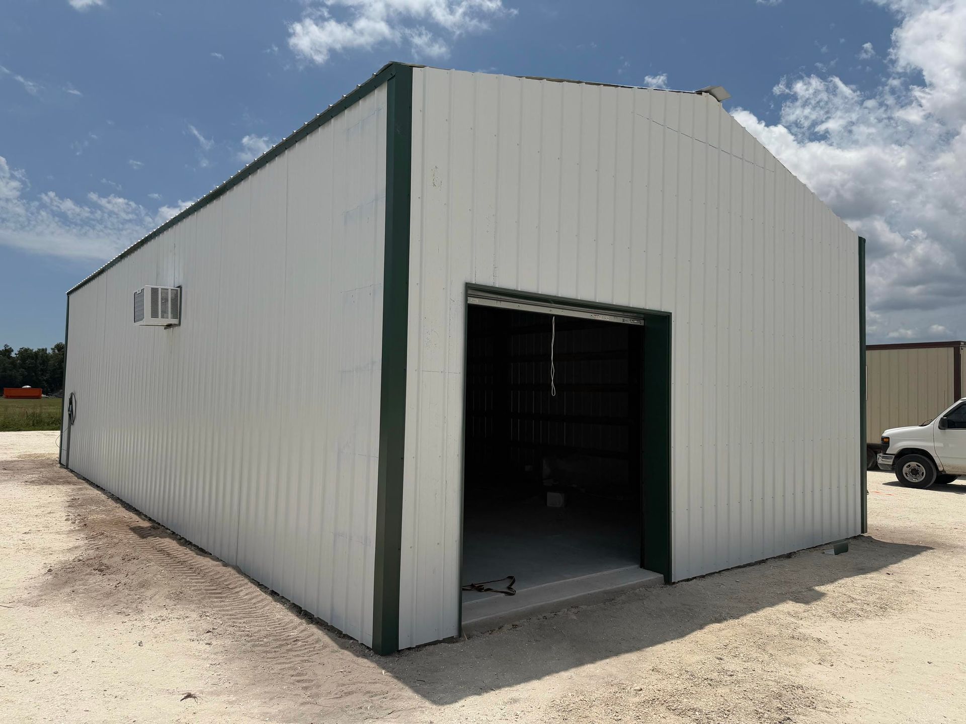 White metal warehouse building with an open garage-style doorway under a blue sky