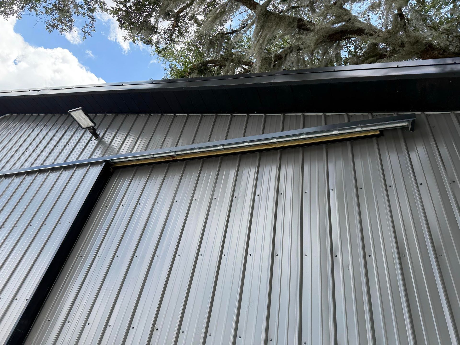 Gray metal roof with a bent gutter under a large tree