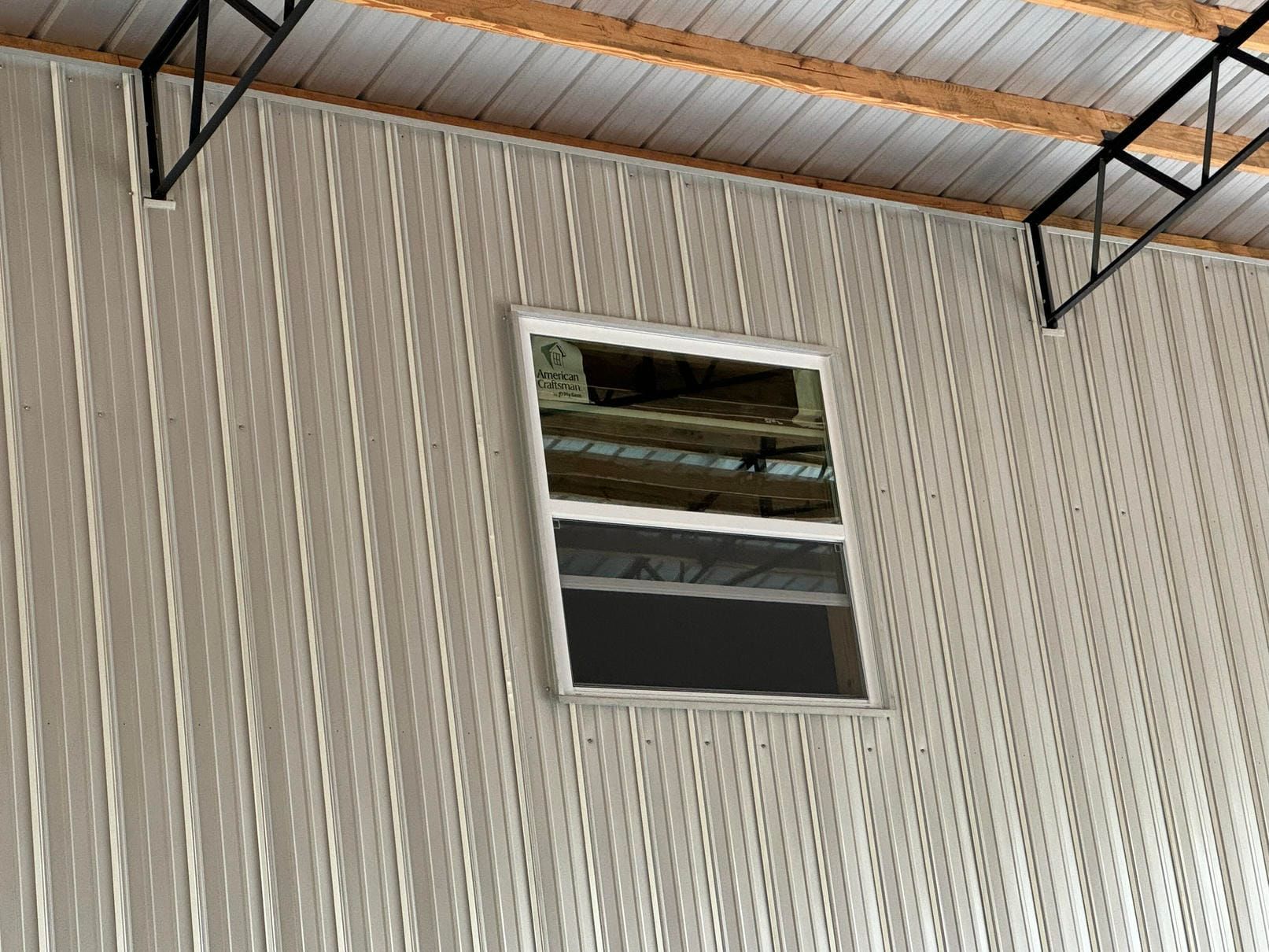 Interior wall with a small rectangular window near the ceiling in a metal building.