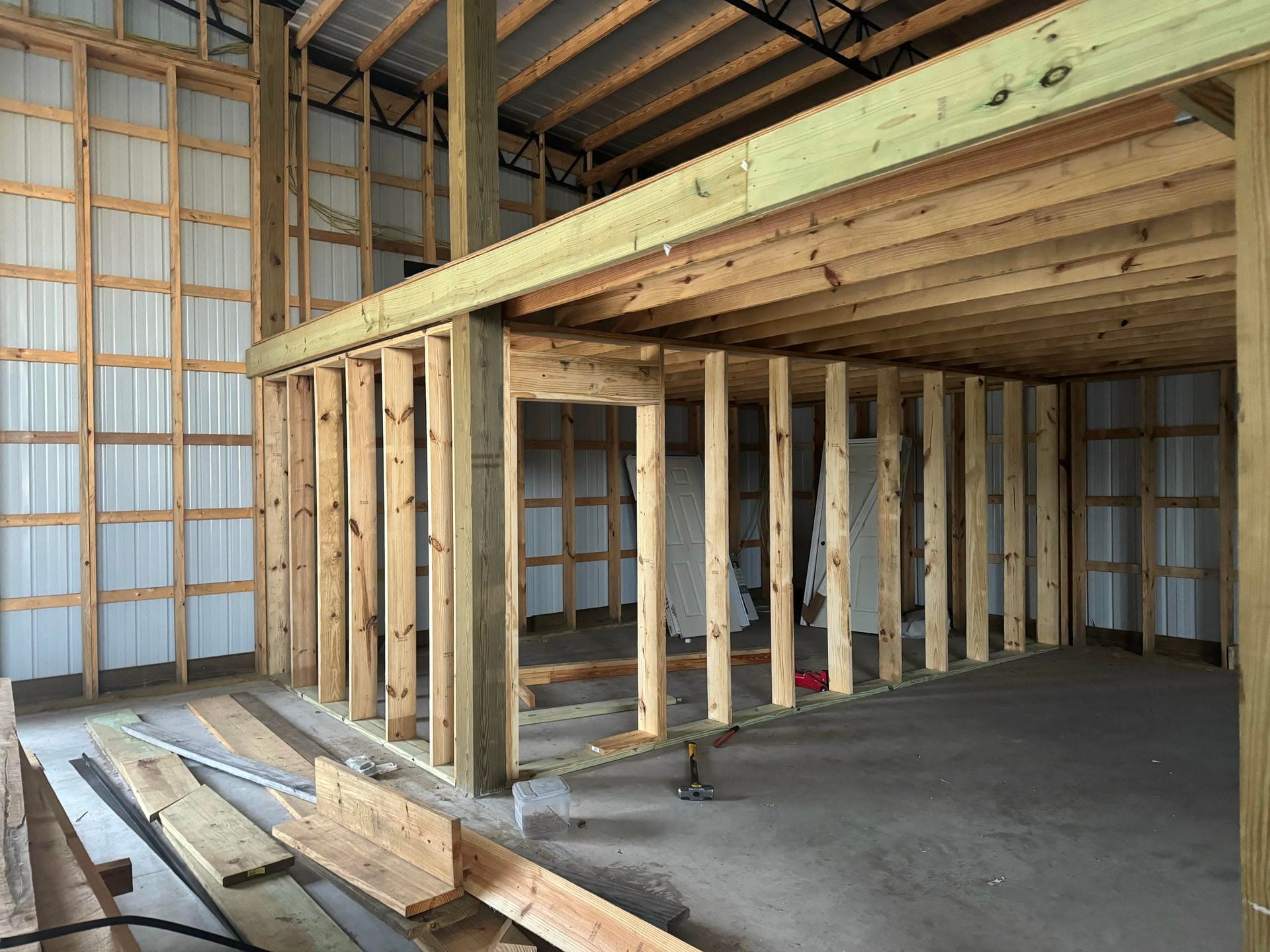 Wood-framed loft under construction inside an unfinished building, with exposed studs and concrete floor