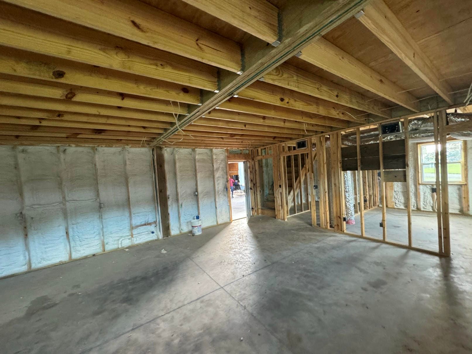 Empty unfinished basement with concrete floor, exposed wood ceiling joists, and framed walls.