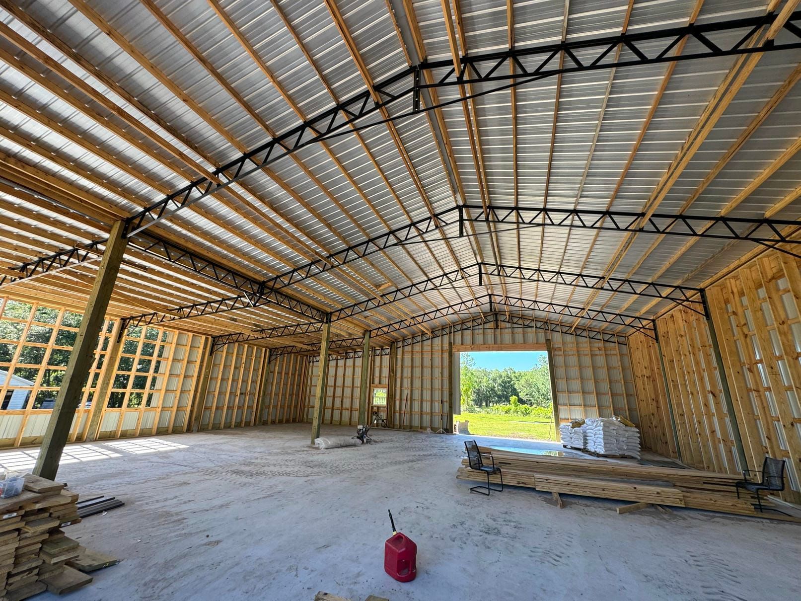 Unfinished metal-framed warehouse interior with insulation, concrete floor, and bright open doorway.