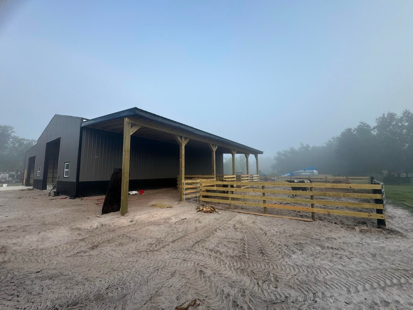 Foggy outdoor farm shed with stacked wooden pallets on a sandy lot