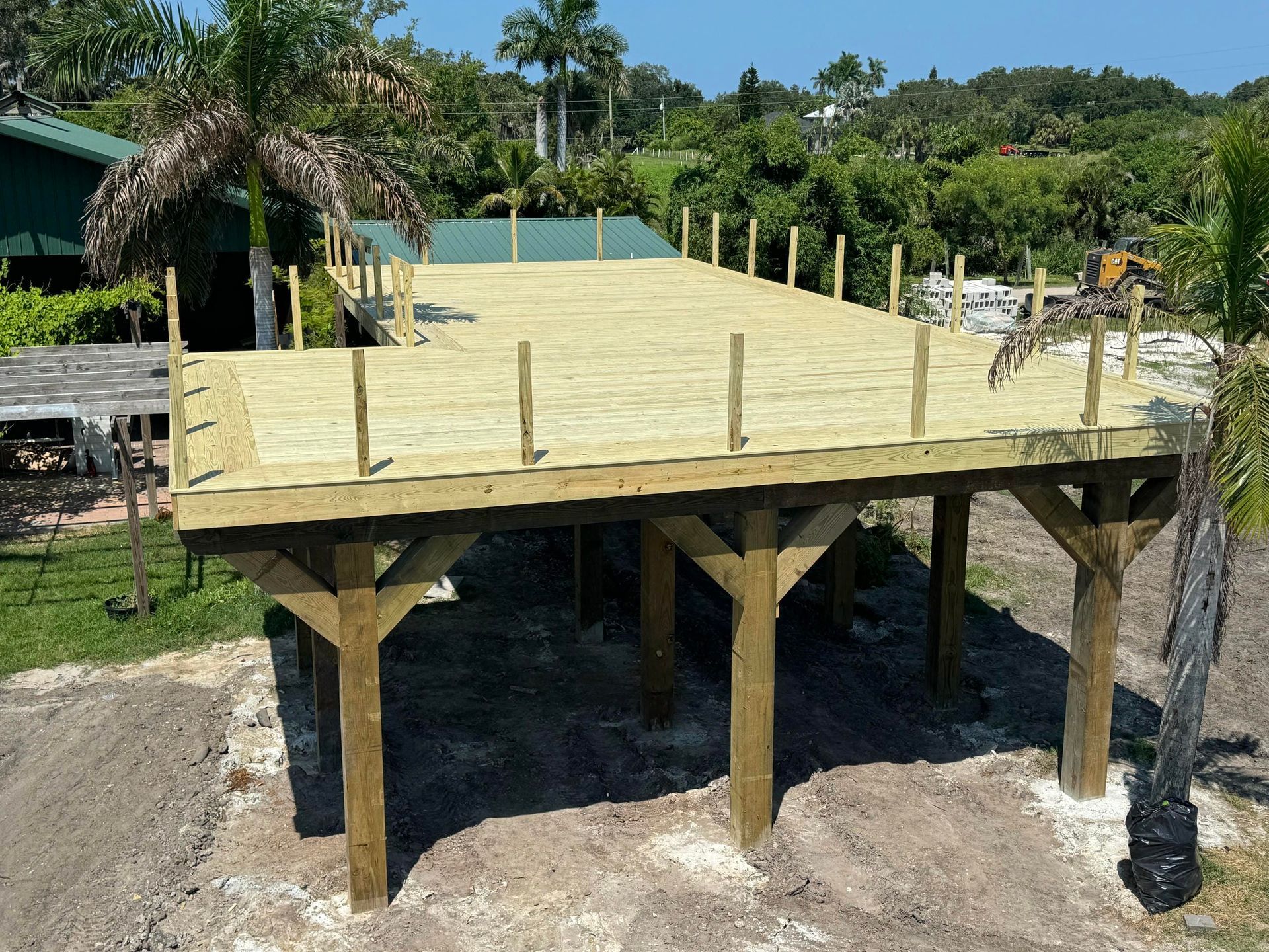 Raised wooden deck under construction on stilts in a tropical outdoor setting