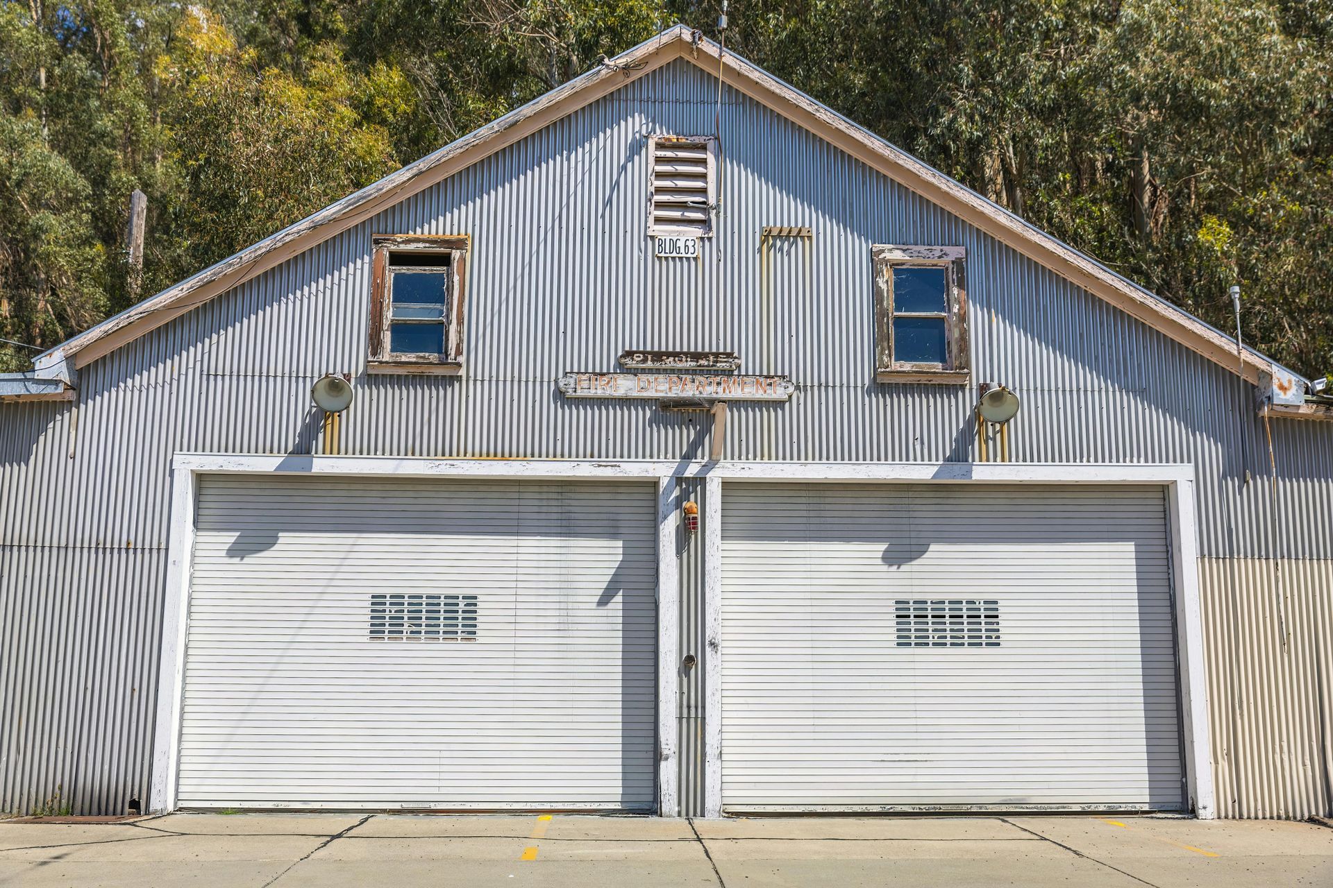 White two-car garage with blue siding and two dormer windows beneath a peaked roof.