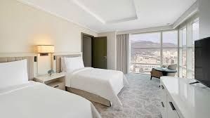 Two twin beds in a modern hotel room with city view.