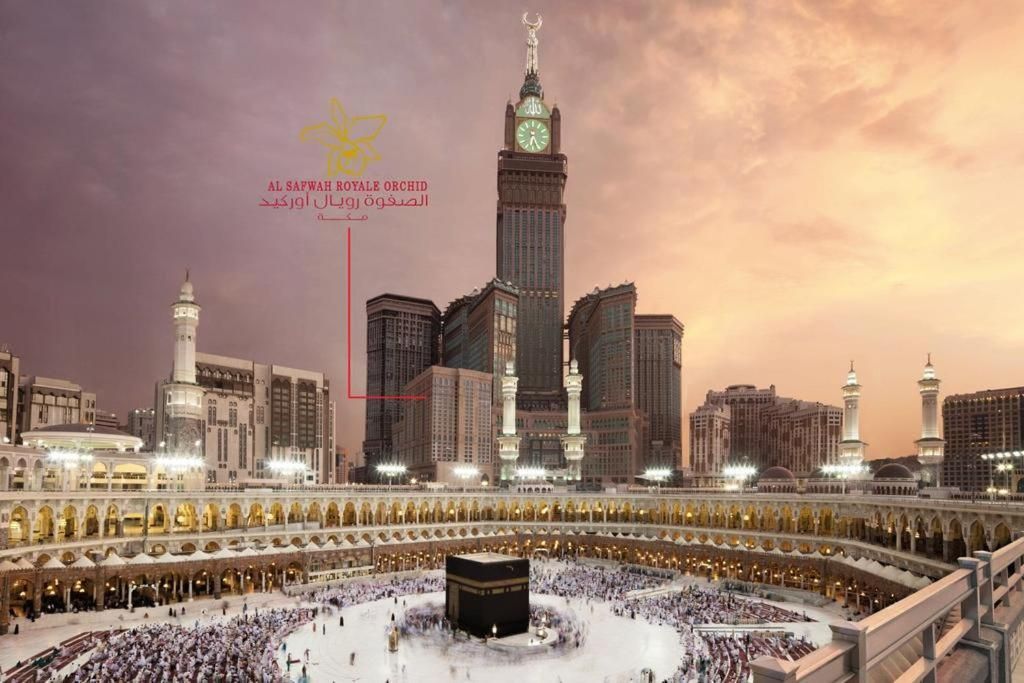 Kaaba in Mecca with clock tower and people circling during sunset.