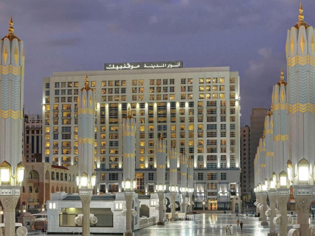 A brightly lit hotel in Medina, Saudi Arabia, surrounded by white pillars and ornate lighting.