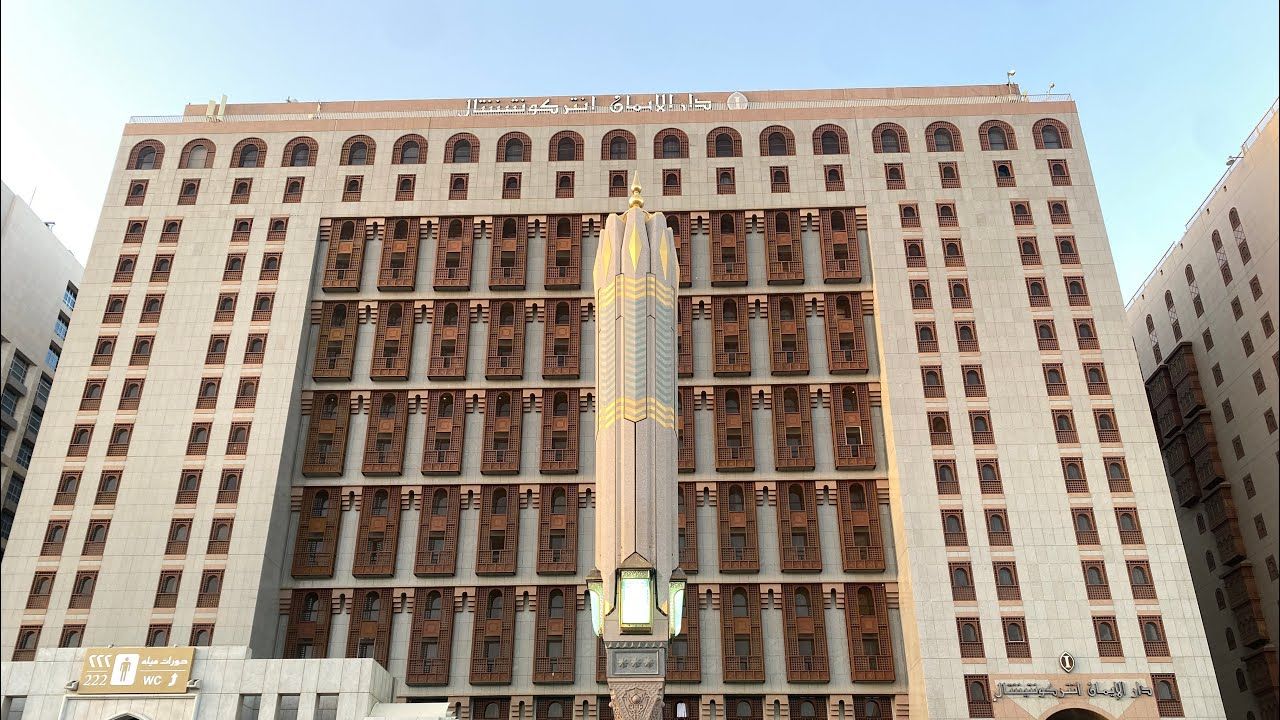 Multi-story beige building with many arched windows and an elongated light fixture in the center.
