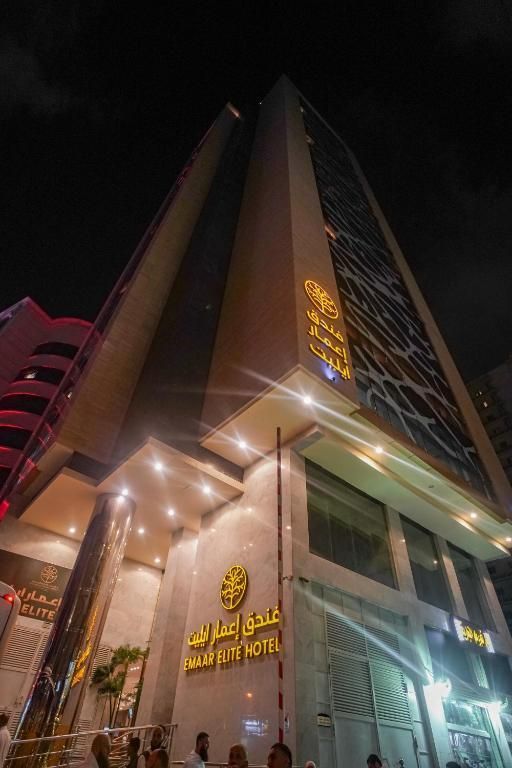 Tall hotel building lit up at night, golden signage, glass facade.