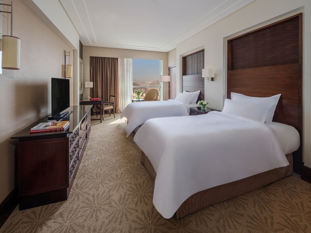 Hotel room with two twin beds, a window with a view, and a dark wood dresser.