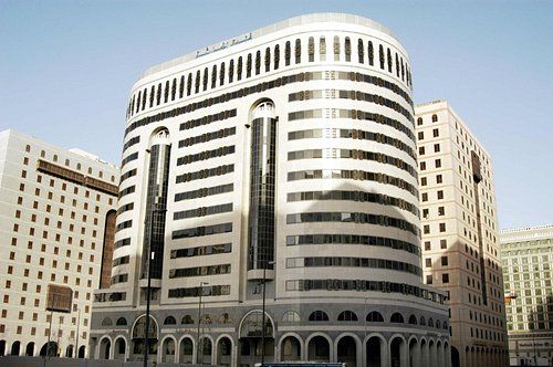 Hotel building with curved facade and arched windows in an urban setting.