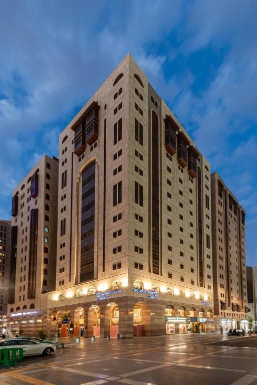 Hotel exterior lit at dusk, featuring a multi-story building with a stone facade and arched windows.