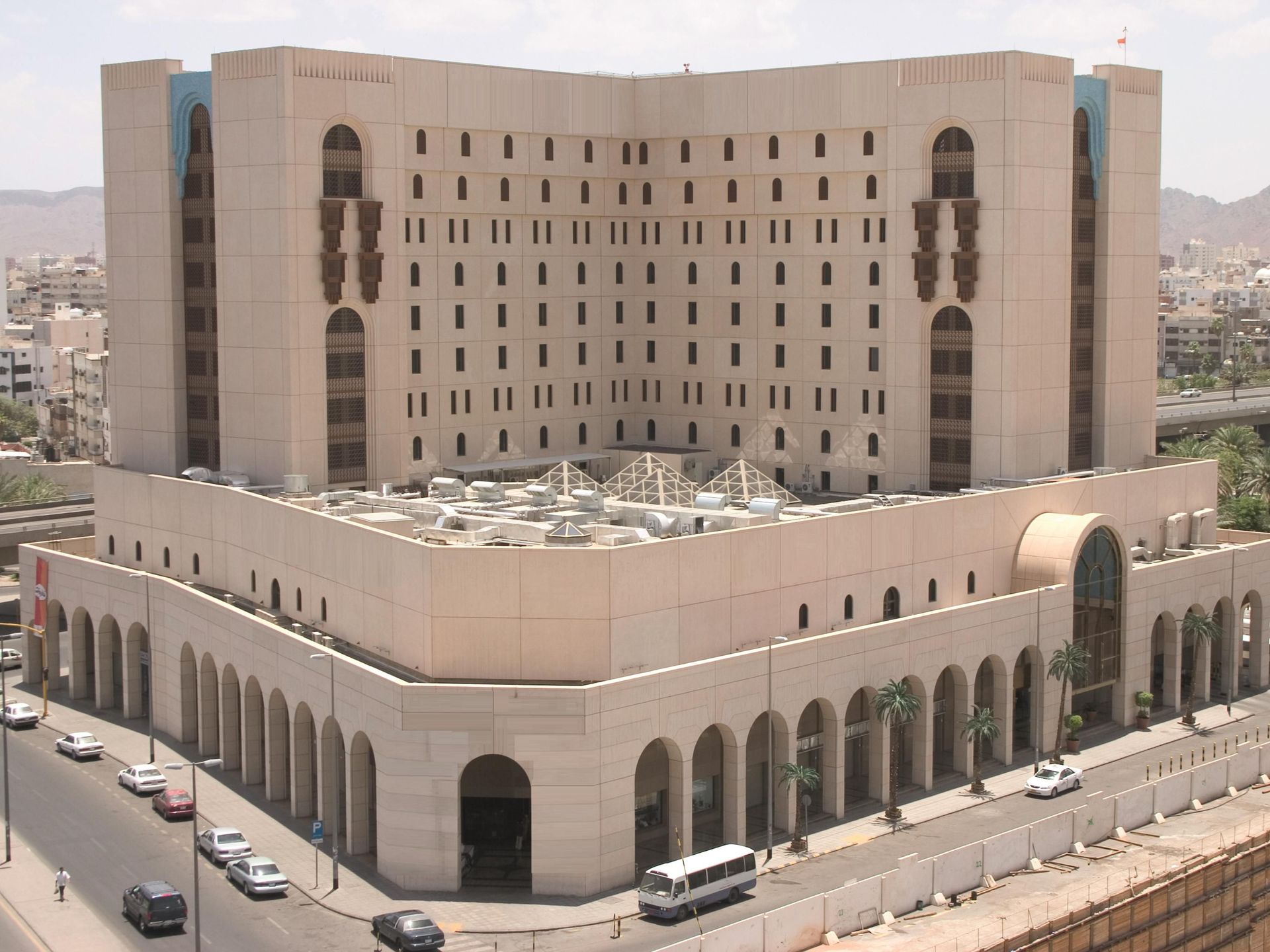Beige building with arched entryways and balconies, overlooking a street with cars; Middle East setting.