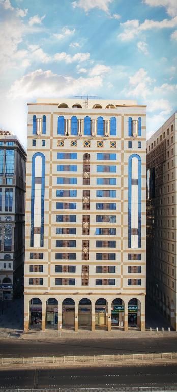 Tall beige building with arched windows, blue sky backdrop.