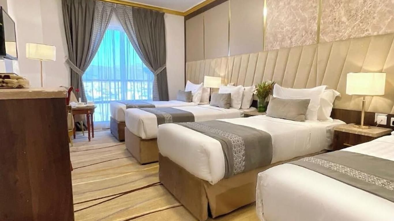 Hotel room with three beds, beige and gray decor, window with curtains.