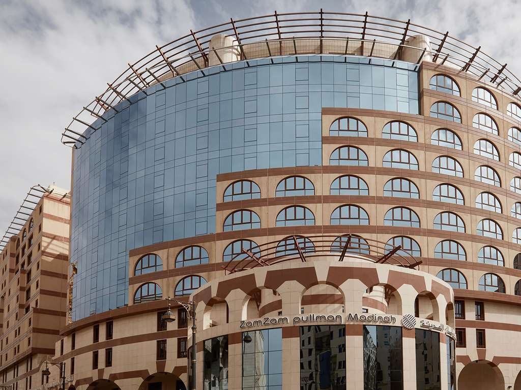 Hotel exterior with large glass facade and rounded tan brick structure.