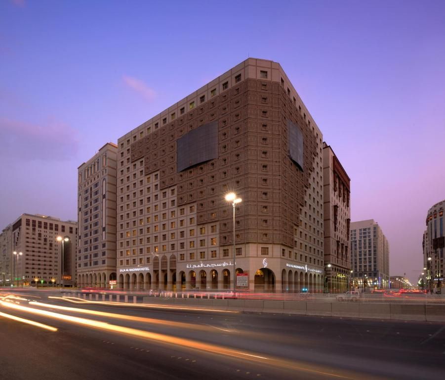 Hotel at dusk with traffic light trails. Brown building with arched entrance. Medina, Saudi Arabia.