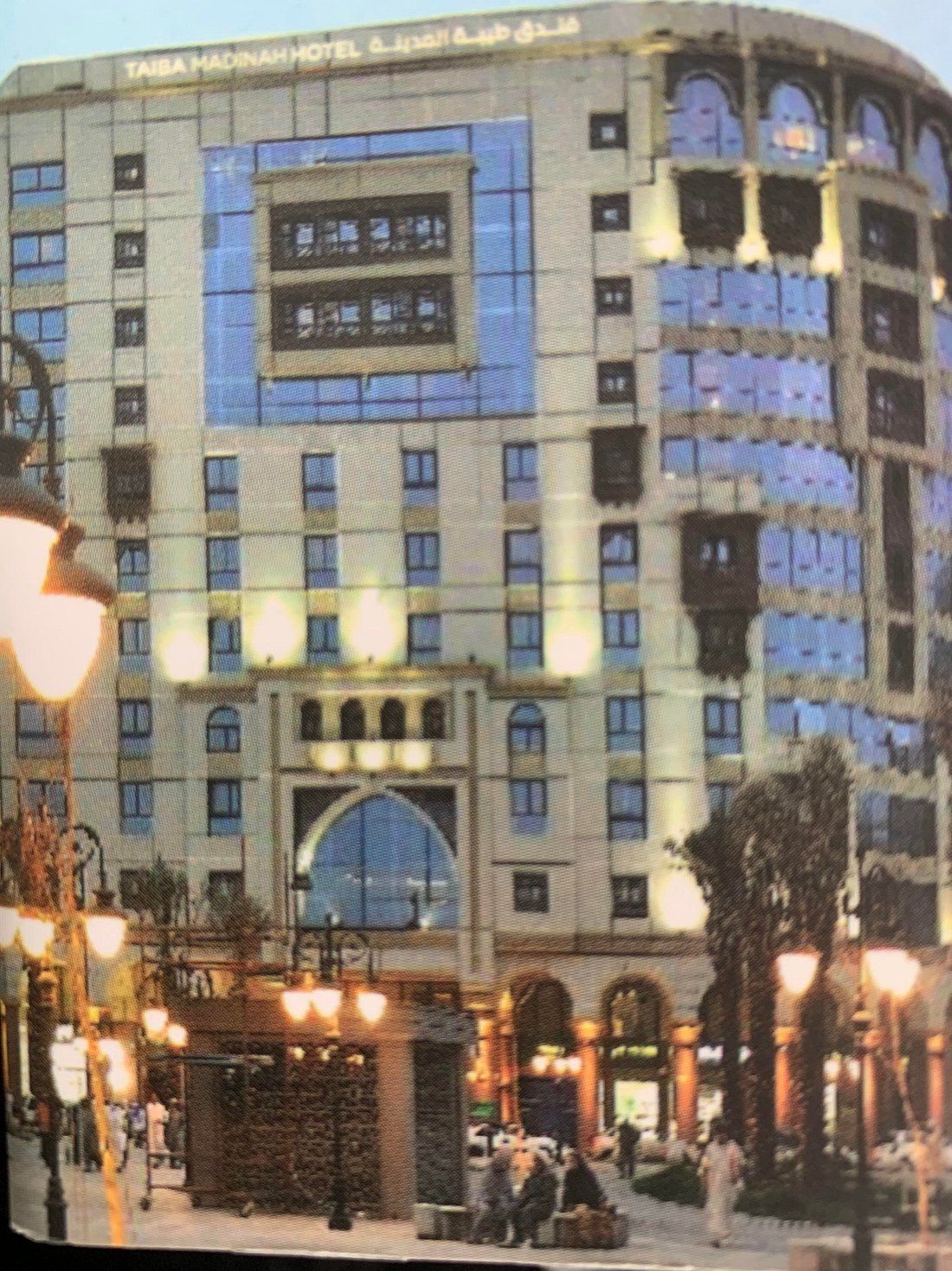 Hotel building, beige with blue windows, lit street in front, Middle East.