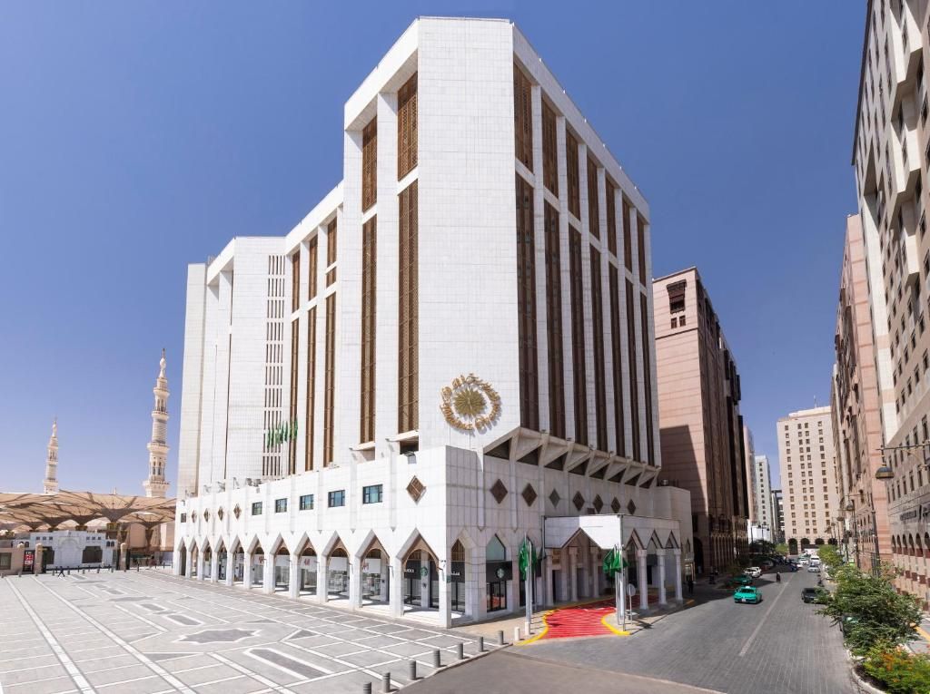 Exterior view of a white building with arched entrance, in a city setting.