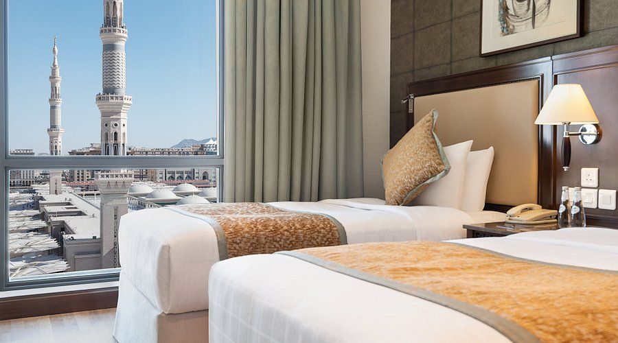 Two twin beds in hotel room with a view of a mosque.