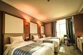 Hotel room with three beds, a window, and a desk.