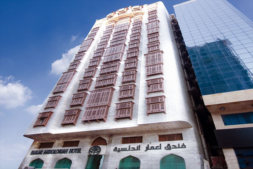 High-rise hotel with traditional wooden balconies, fronted by a modern glass building in a cityscape.