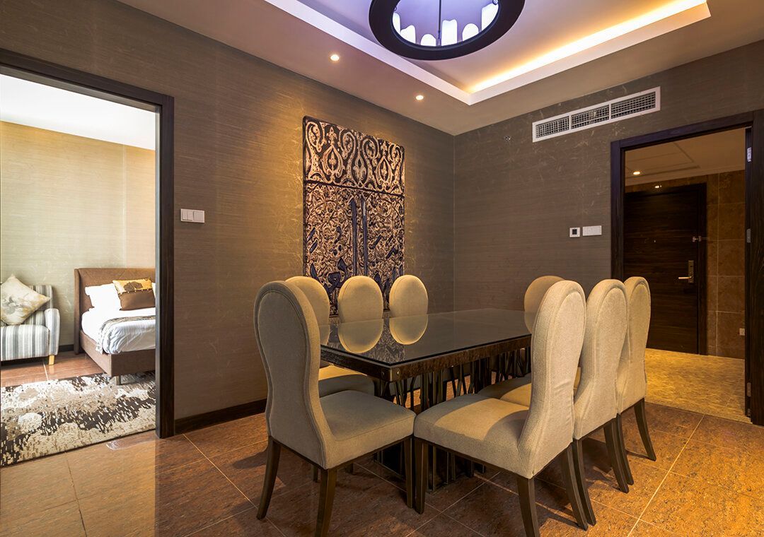 Dining room with a table, chairs, artwork, and open doors to other rooms. Brown walls and beige chairs.