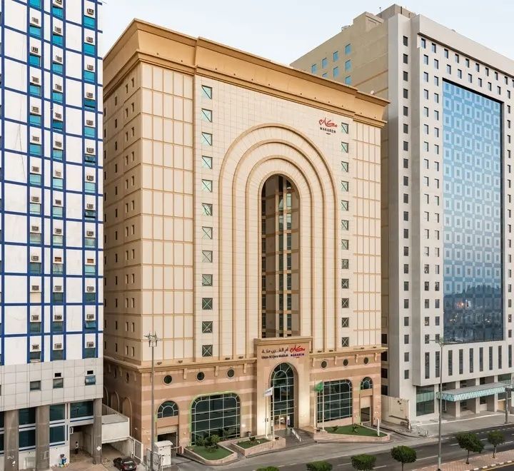 Hotel building with arched facade, tan and brown exterior, and multiple windows.