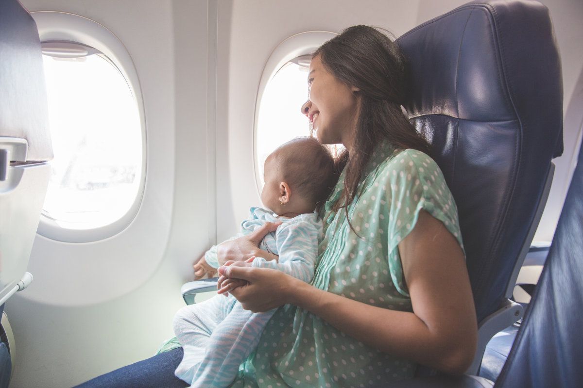 A woman is holding a baby on an airplane.
