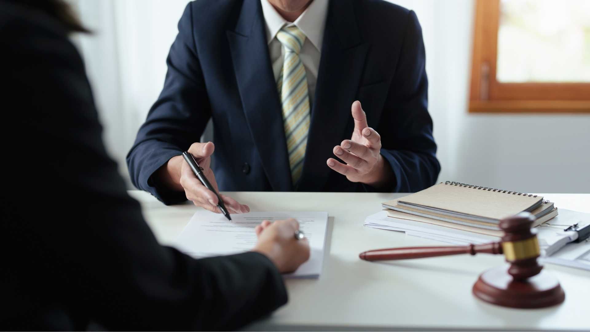 A man in a suit and tie is sitting at a table talking to a woman.