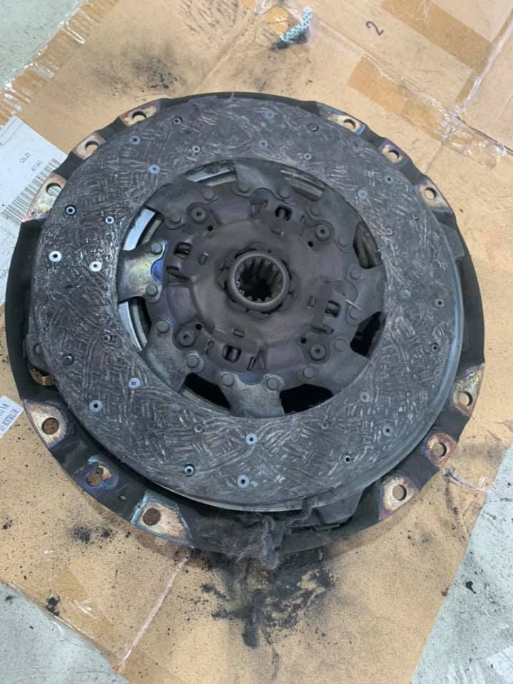 Worn Clutch Disc With Visible Wear and Tear, Covered in Dark Debris — A.M.D. Automotive Services in Mackay, QLD