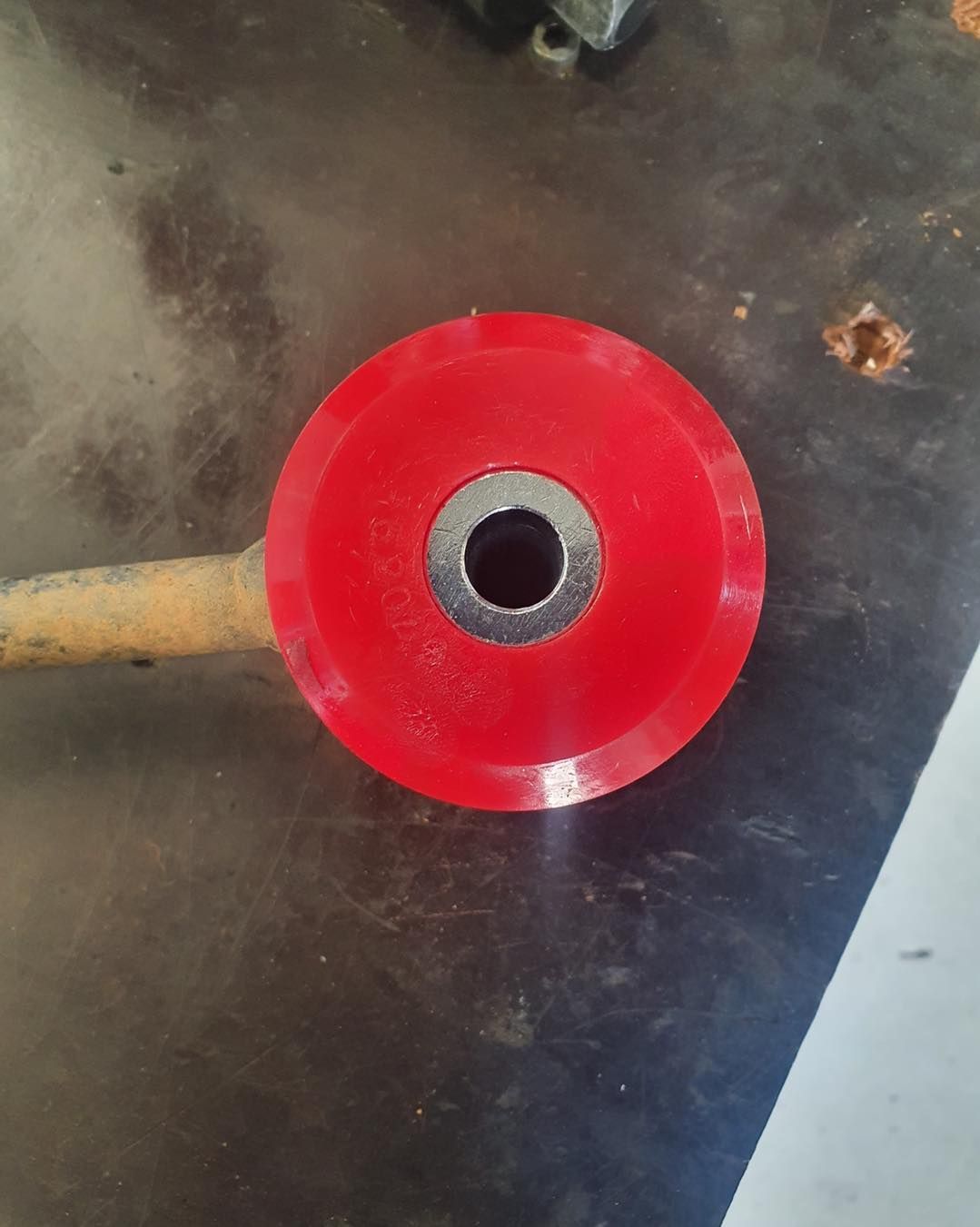Red Polyurethane Bushing With a Metal Sleeve on a Workbench — A.M.D. Automotive Services in Moranbah, QLD