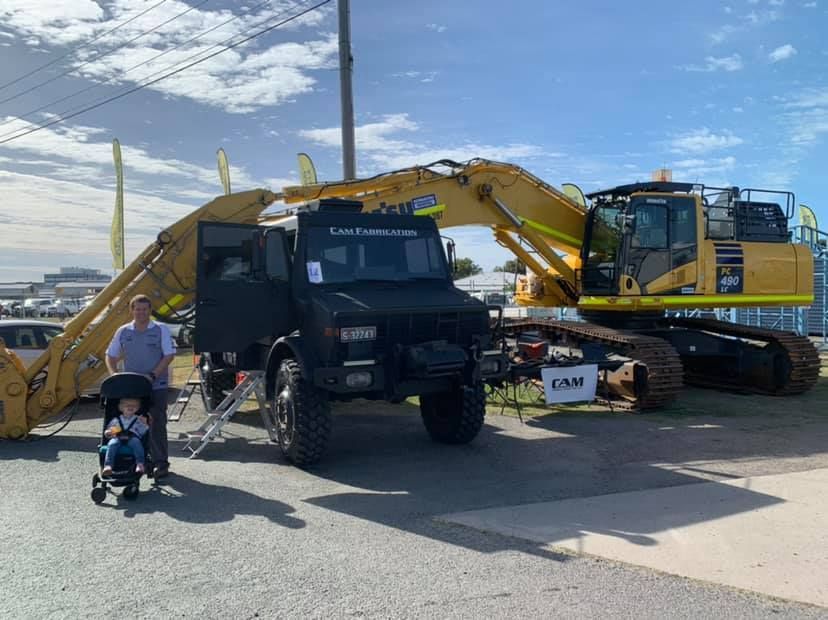 A Man and a Child in a Stroller Pose Next to a Black Truck — A.M.D. Automotive Services in Mackay, QLD