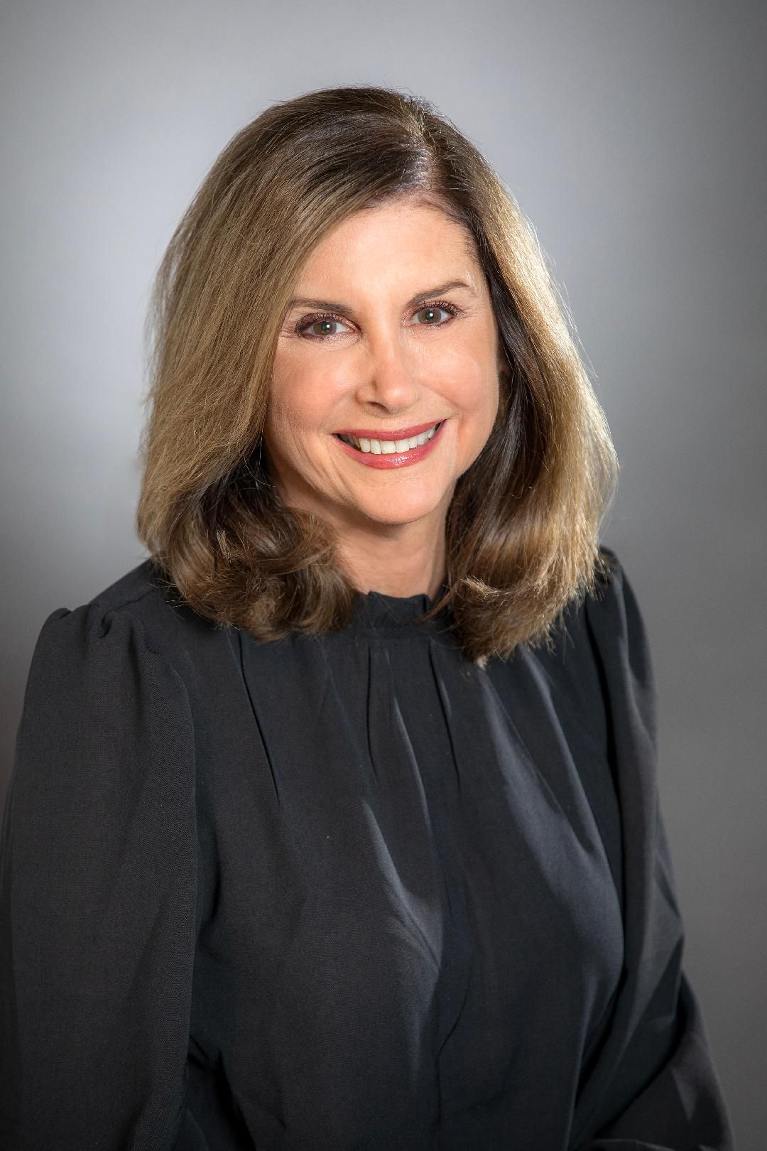 A woman in a black shirt is smiling for the camera.