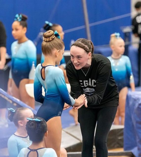 A woman wearing a black egac shirt talks to a young girl