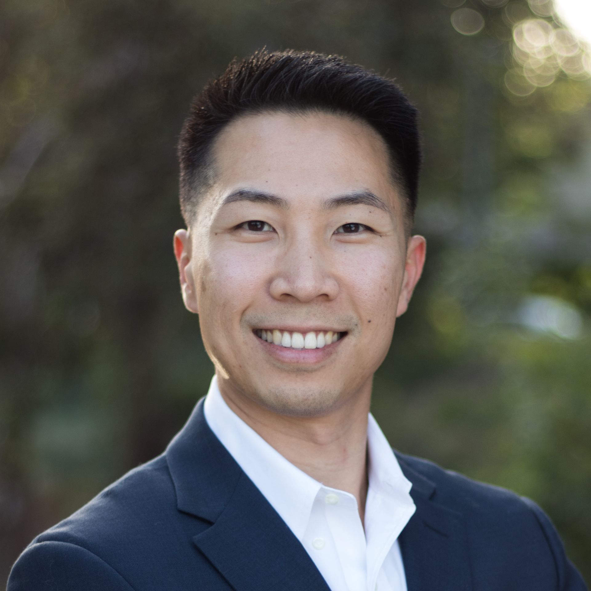 A man in a suit and white shirt is smiling for the camera.