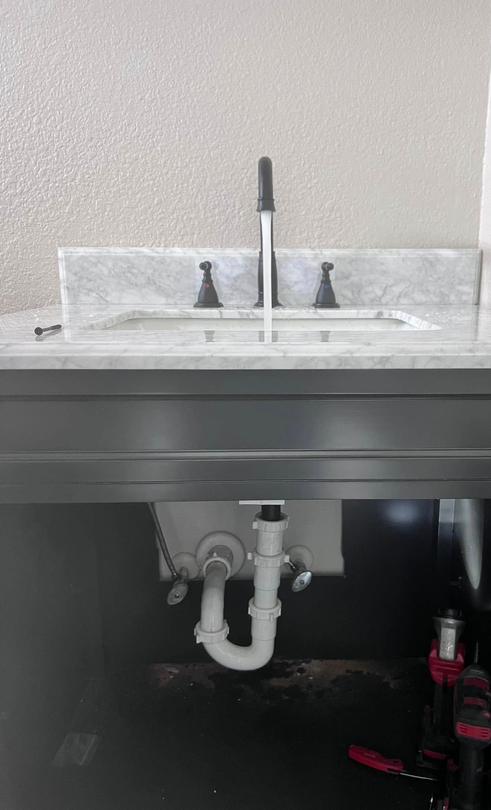 Bathroom sink with a central faucet and exposed white drain pipes beneath the counter.