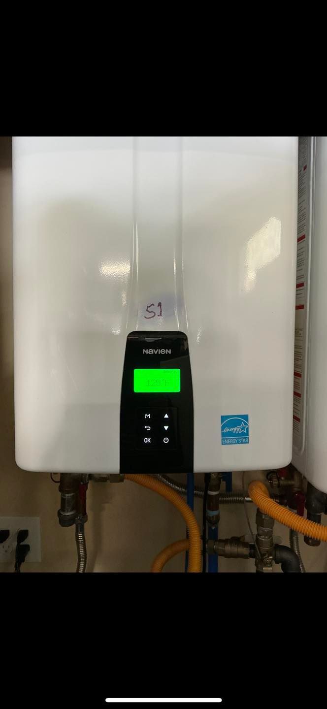 Wall-mounted white boiler with a small green-lit control panel and pipes underneath.