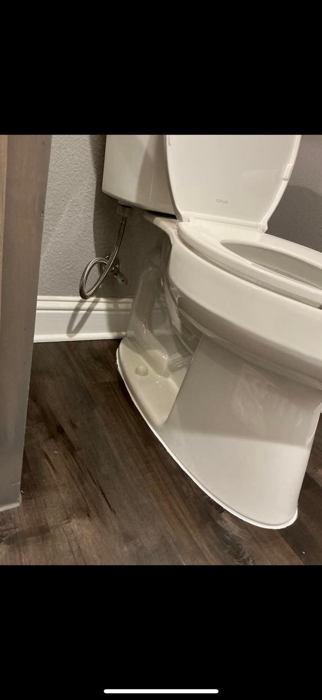 Partially open toilet seat in a bathroom with dark wood floor and a visible cord beside it