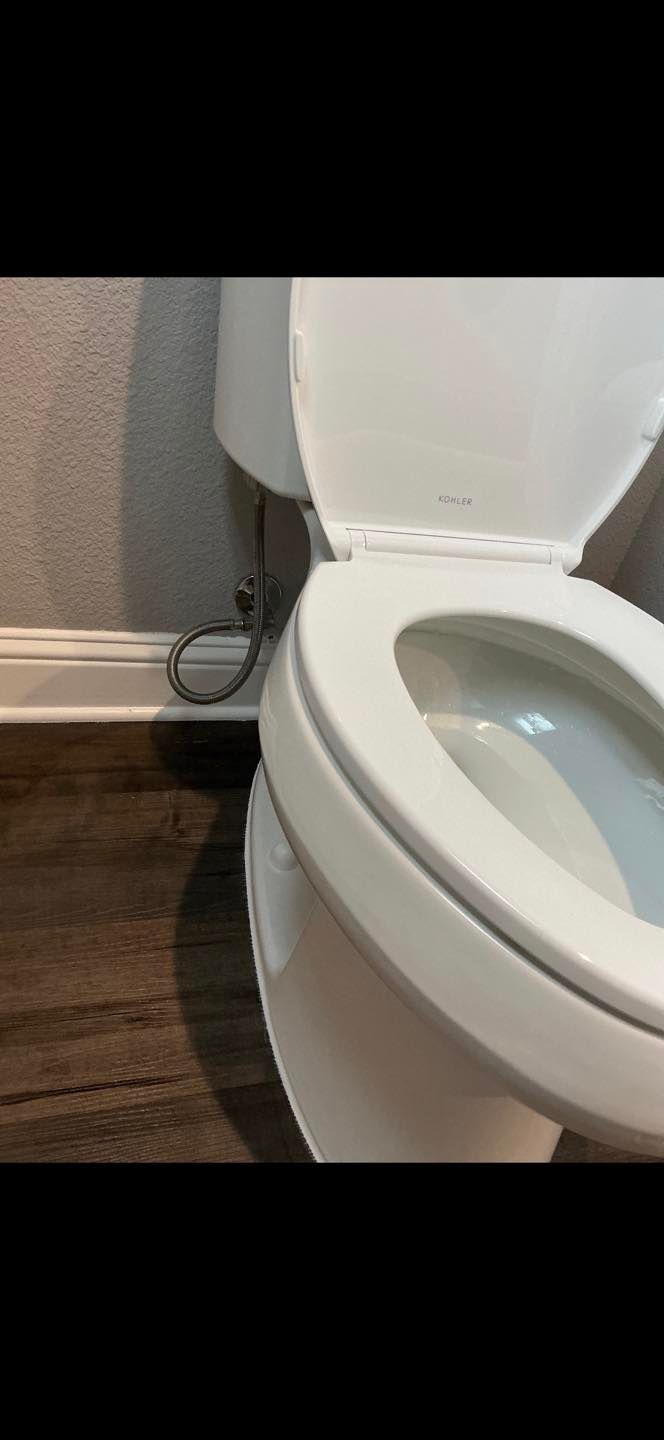 White toilet in a small bathroom with dark wood flooring and gray walls